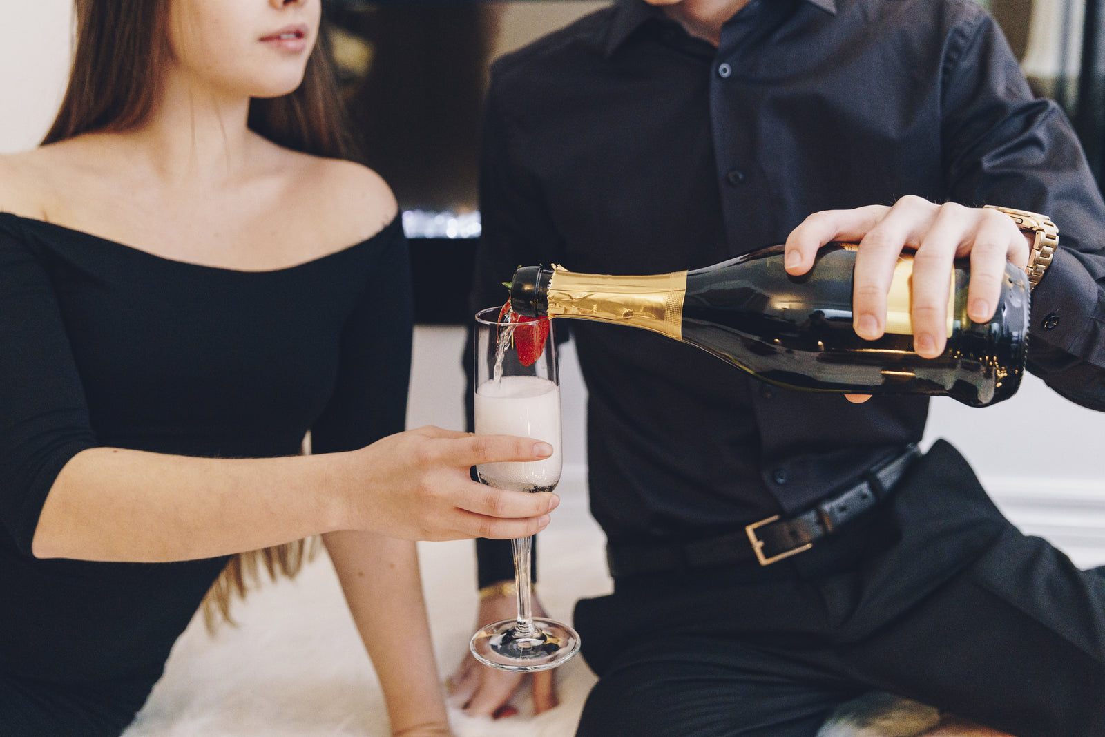 A couple pouring champagne together